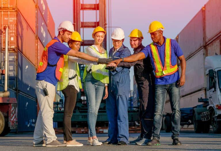 Group of man and woman in cargo container area join hands together in the concept of best collaborate for working
